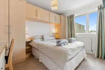 a bedroom with a bed with a desk and a window at Macalby Cottage in Padstow
