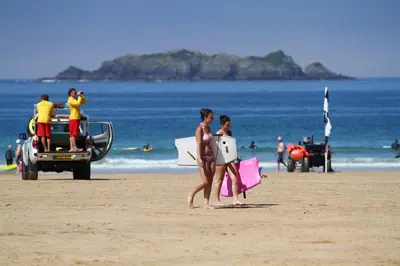 two women walking on the beach with their surfboards at Macalby Cottage in Padstow