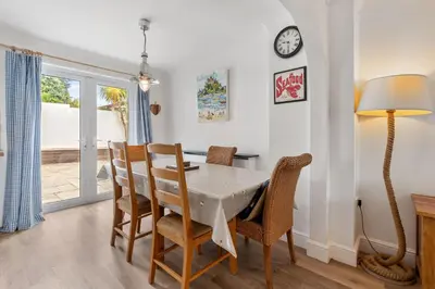 a dining room with a table and chairs and a clock at Macalby Cottage in Padstow