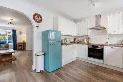 a kitchen with a blue refrigerator and white cabinets at Macalby Cottage in Padstow