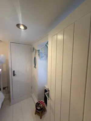 a bathroom with a white closet and a door at Happy days cottage in St Ives