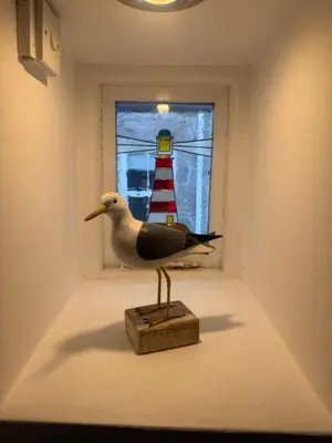 a bird statue in front of a window with a lighthouse at Happy days cottage in St Ives