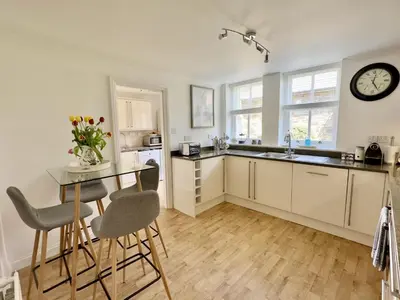 a kitchen with a table and a clock on the wall at Heather House in Padstow