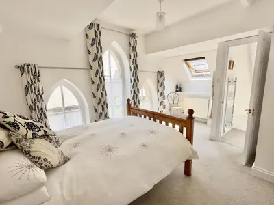 a bedroom with a bed and two windows at Heather House in Padstow