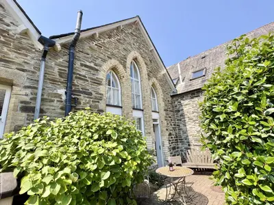a brick building with a table and two large bushes at Heather House in Padstow