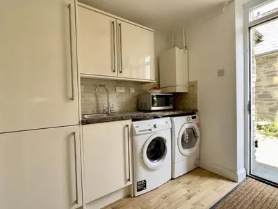 a kitchen with a washing machine and a microwave at Heather House in Padstow
