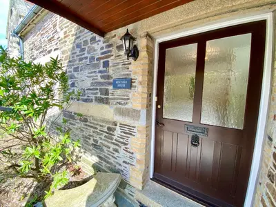 a wooden door of a brick building with a sign on it at Heather House in Padstow