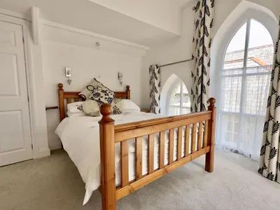 a bedroom with a bed and a large window at Heather House in Padstow