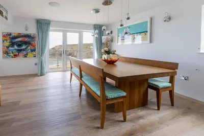 a dining room with a wooden table and chairs at Tides Edge in Portreath