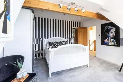 a bedroom with a white bed and striped walls at Tides Edge in Portreath