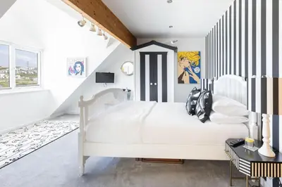a bedroom with a white bed with striped walls at Tides Edge in Portreath