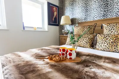 a tray of food and two cups on a bed at Tides Edge in Portreath