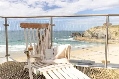 a rocking chair sitting on a balcony overlooking the beach at Tides Edge in Portreath
