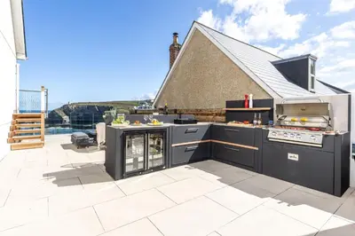 an outdoor kitchen on a patio with a roof at Tides Edge in Portreath