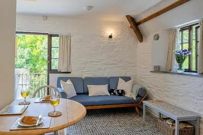 a living room with a blue couch and a table at Finest Retreats - Rowella Cottage in Blisland