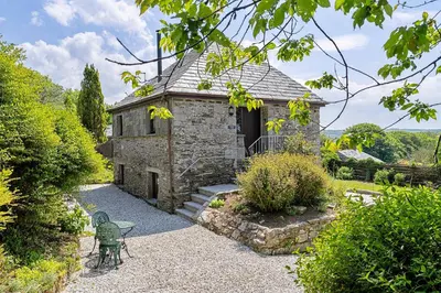 a stone building with a table and chairs in a garden at Finest Retreats - Rowella Cottage in Blisland