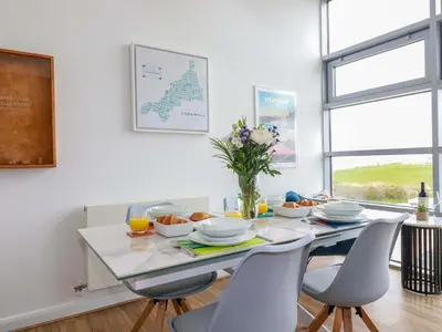 a white dining room with a table and chairs at Penthouse 46Zinc - Headland View in Newquay