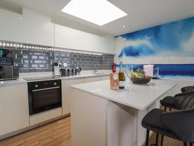a kitchen with a white counter and a blue wall at Penthouse 46Zinc - Headland View in Newquay