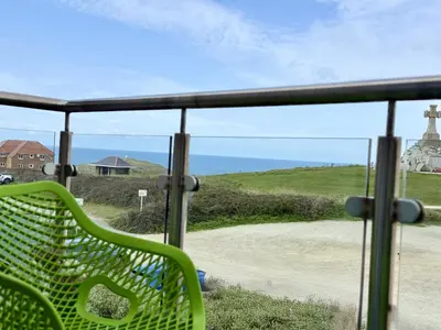 a green bench sitting on a balcony looking out at the ocean at Penthouse 46Zinc - Headland View in Newquay
