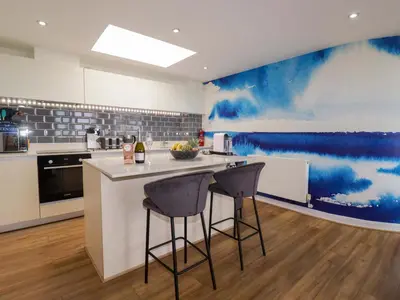 a kitchen with a counter and two bar stools at Penthouse 46Zinc - Headland View in Newquay