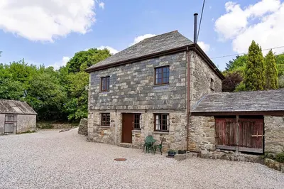 an old stone building with a chair in front of it at Finest Retreats - Demelza Cottage in Blisland