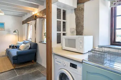 a kitchen with a washing machine and a couch at Finest Retreats - Demelza Cottage in Blisland