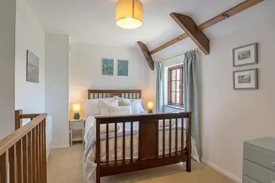 a bedroom with a bed and a window and a staircase at Finest Retreats - Demelza Cottage in Blisland
