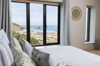 a bedroom with a large window with a view of the ocean at Tamarind Tide in Portreath