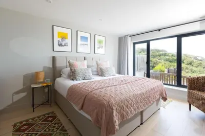 a bedroom with a bed and a large window at Tamarind Tide in Portreath
