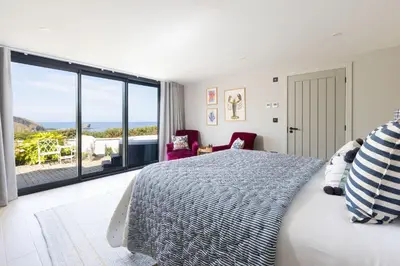 a bedroom with a bed and a view of the ocean at Tamarind Tide in Portreath