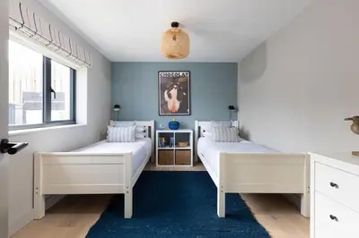 two beds in a bedroom with blue walls at Tamarind Tide in Portreath