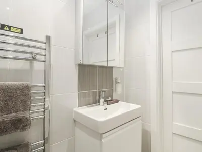 a white bathroom with a sink and a mirror at The Black Barnacle in Redruth
