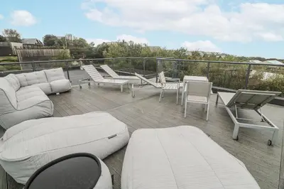 a patio with chairs and couches on a deck at The Black Barnacle in Redruth