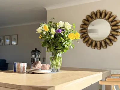 a vase of flowers on a table with a mirror at 42 Little Trelyn in Wadebridge