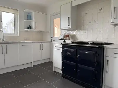 a kitchen with white cabinets and a black stove at 42 Little Trelyn in Wadebridge