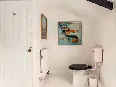 a bathroom with a toilet and a painting on the wall at Sunnyside Cottage Retreat in St Austell