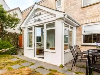 a small white building with a table and chairs at Sunnyside Cottage Retreat in St Austell