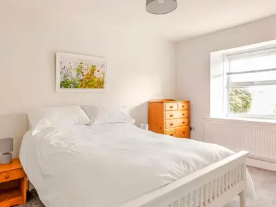 a white bedroom with a white bed and a window at Sunnyside Cottage Retreat in St Austell
