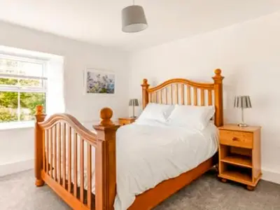 a bedroom with a wooden bed and a window at Sunnyside Cottage Retreat in St Austell
