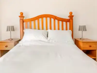 a bed with two lamps on two night stands at Sunnyside Cottage Retreat in St Austell