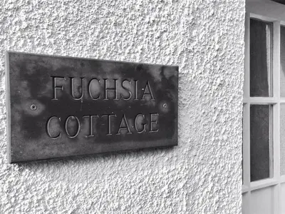 a metal sign on the side of a building at Fuchsia Cottage in Saint Mawes