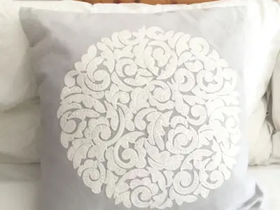 a white pillow with a white design on a bed at Fuchsia Cottage in Saint Mawes