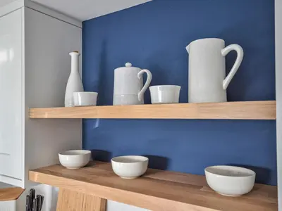 a shelf with white vases and bowls on it at Fuchsia Cottage in Saint Mawes