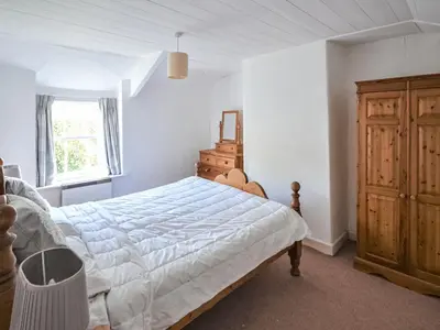 a bedroom with a bed and a dresser and a window at Fuchsia Cottage in Saint Mawes