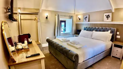 a bedroom with a large bed and a mirror at Rising Sun Inn - Bronn Ewhella in Altarnun