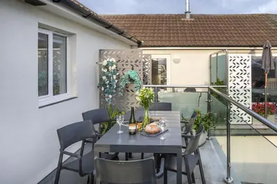 a patio with a table and chairs on a balcony at Sunset View - Sea View - Pet Friendly - Free WiFi - Free Parking in Marazion