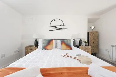a bedroom with a large white bed with a chandelier at Sunset View - Sea View - Pet Friendly - Free WiFi - Free Parking in Marazion