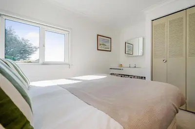 a white bedroom with a large bed and a window at 5 Bed in Trebetherick oc-t33296 in Polzeath