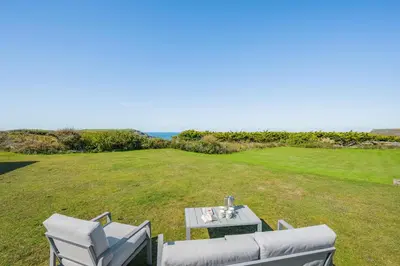 a table and chairs in a field with the ocean at 5 Bed in Trebetherick oc-t33296 in Polzeath