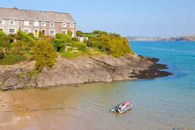 a small boat in the water next to a house at Penn Cottage perfect for North Cornwall trips in Camelford